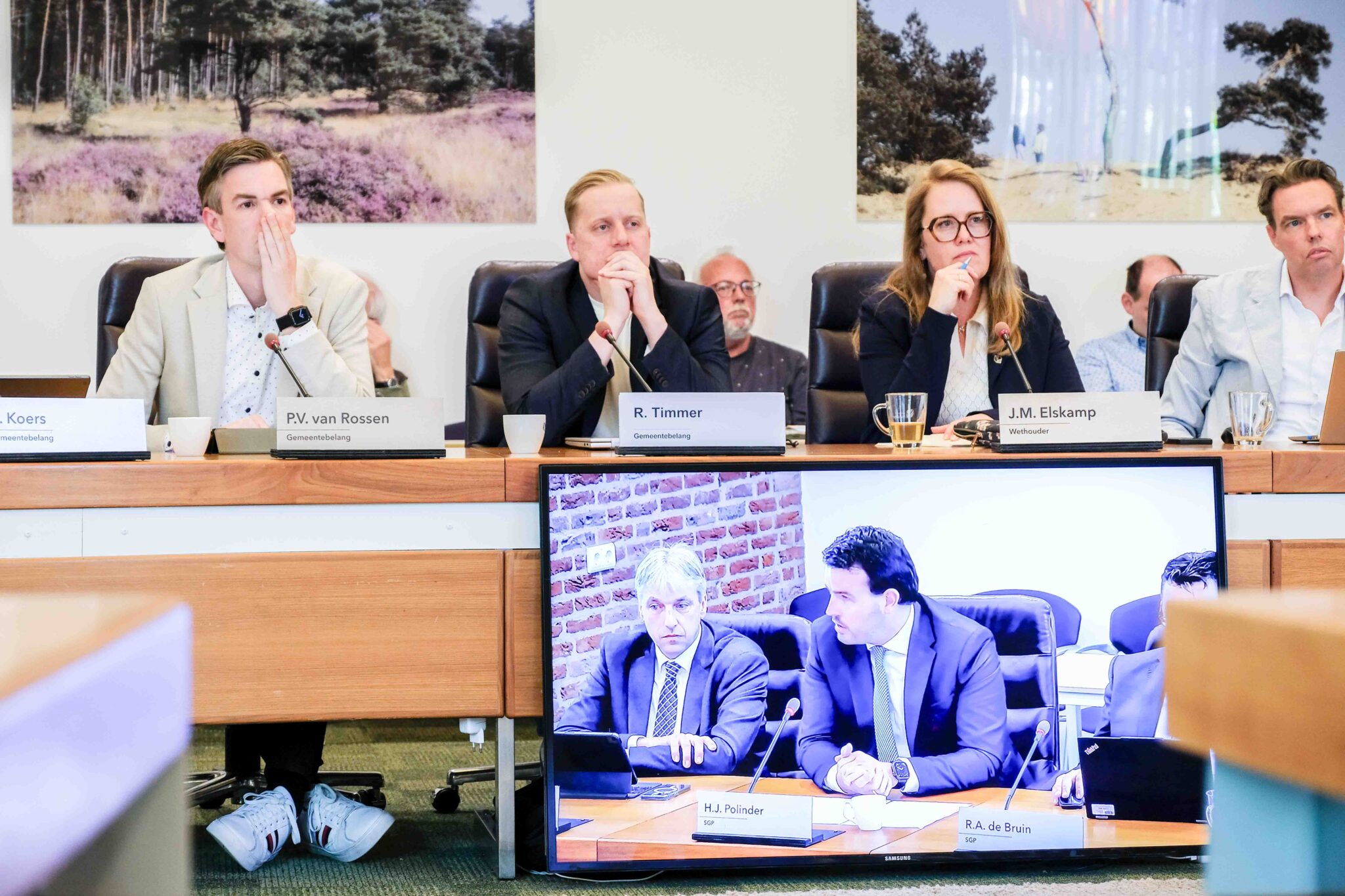 Raadsleden van Gemeentebelang en ChristenUnie luisteren tijdens de informele raadsvergadering in Nunspeet. Op het beeldscherm op de voorgrond SGP fractievoorzitter en wethouder Groothuis